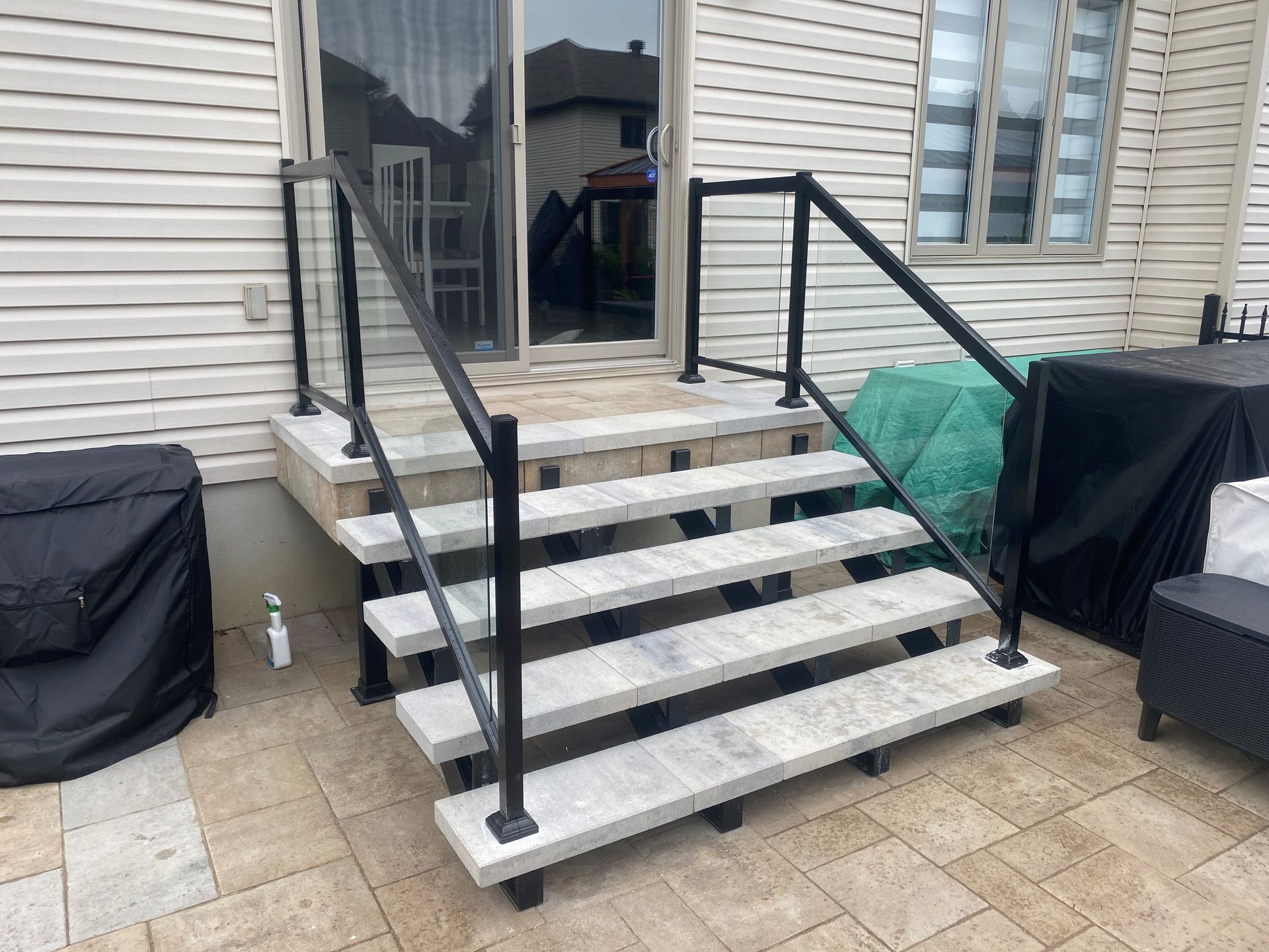 Un ensemble d'escaliers menant à un patio avec une balustrade noire.