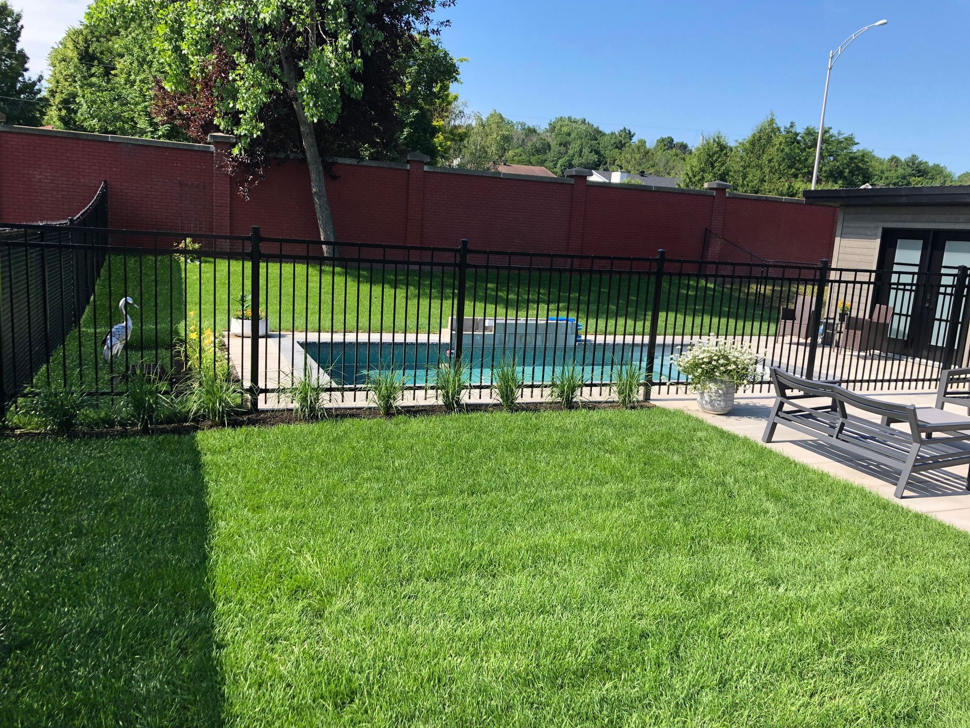 Une cour arrière avec une piscine et une clôture qui l'entoure.