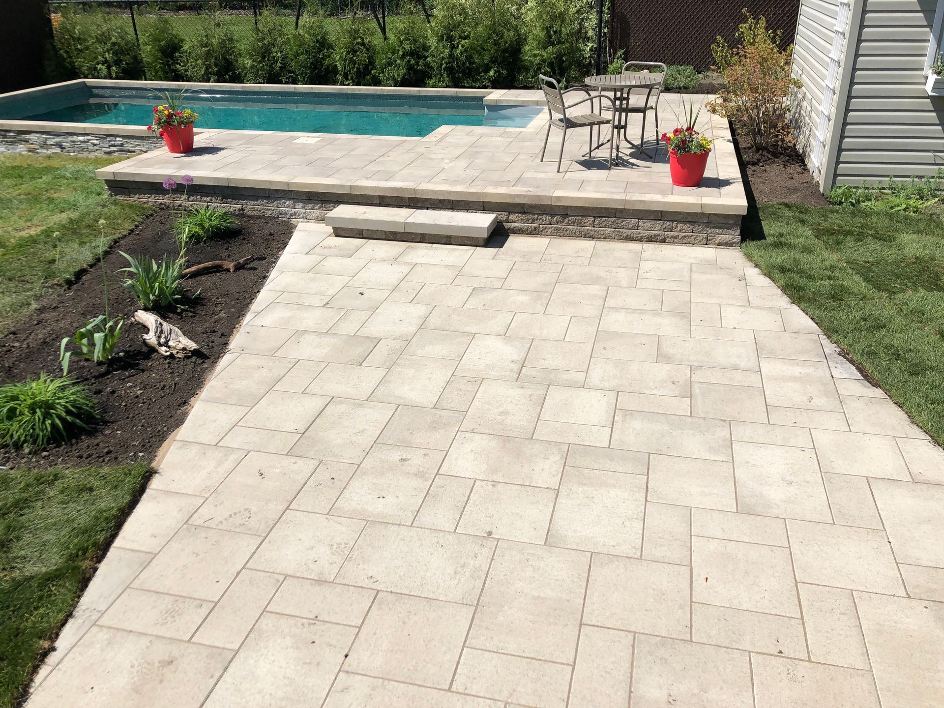 Un patio avec une table et des chaises à côté d'une piscine.