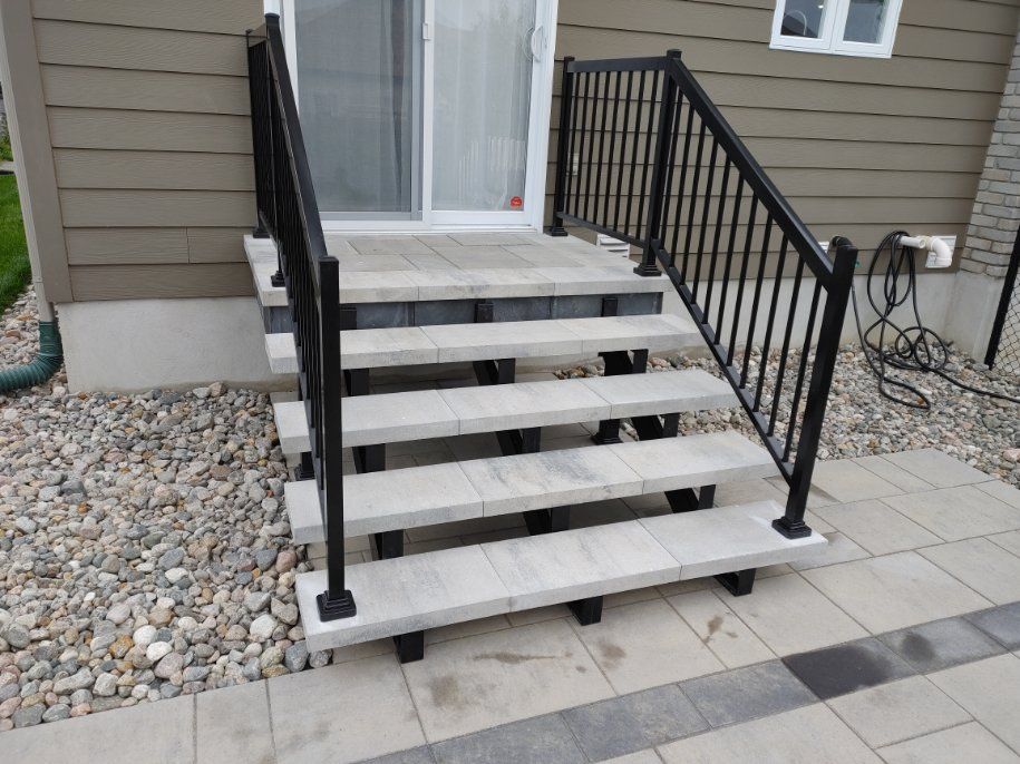 Un escalier menant à une maison avec une rampe noire.