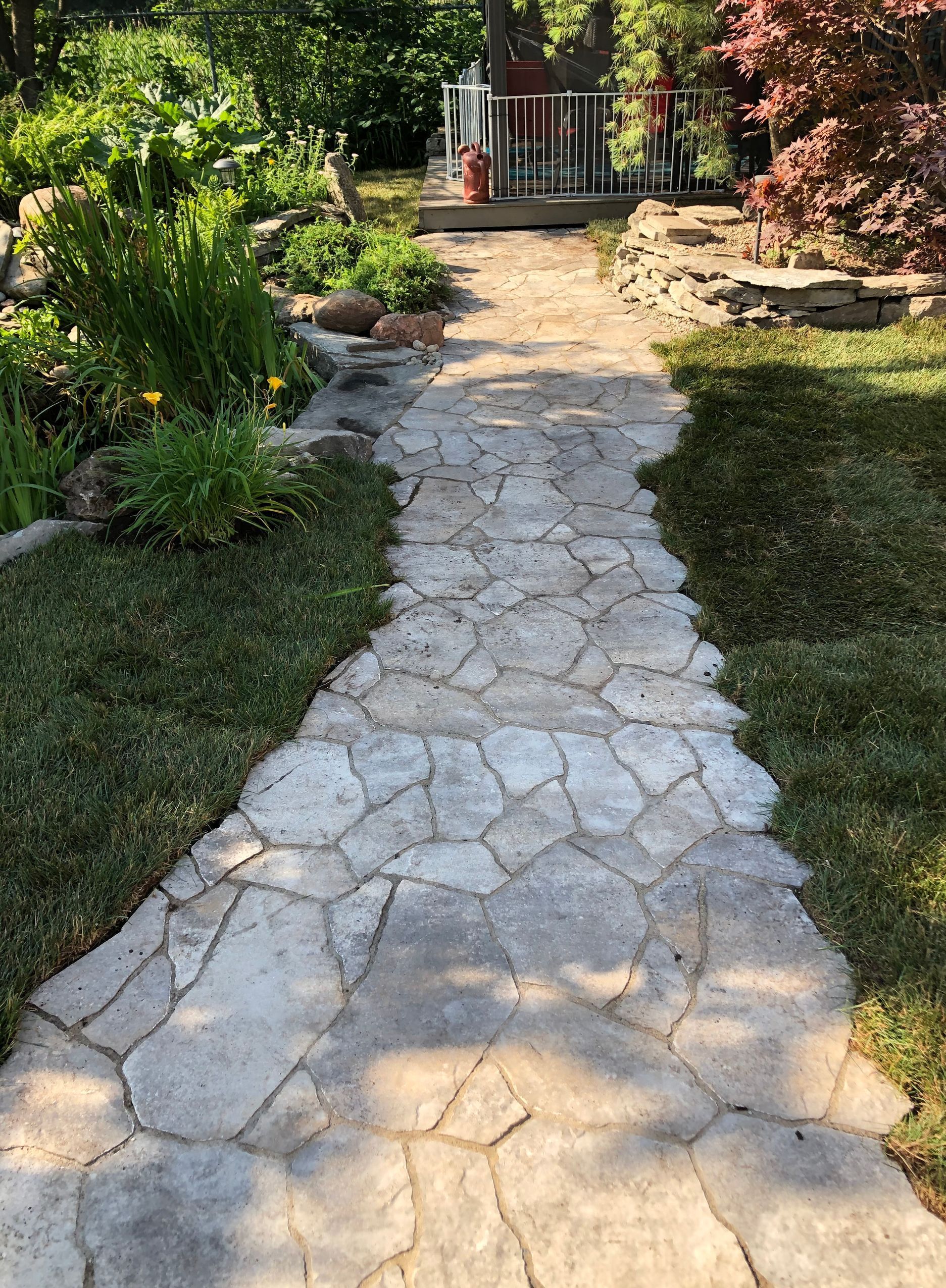 A stone walkway leading to a house in a backyard.