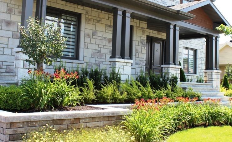 Une grande maison en briques avec un porche et des fleurs devant