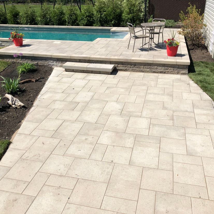 Un patio avec une table et des chaises à côté d'une piscine