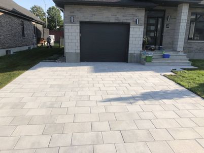 A driveway in front of a house with a black garage door.