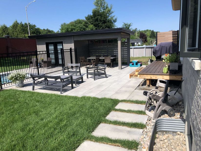 A backyard with a patio , picnic tables , and a gazebo.