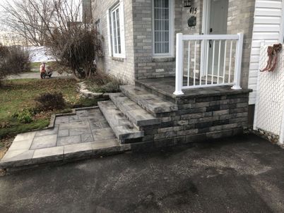 A brick porch with stairs and a white railing.
