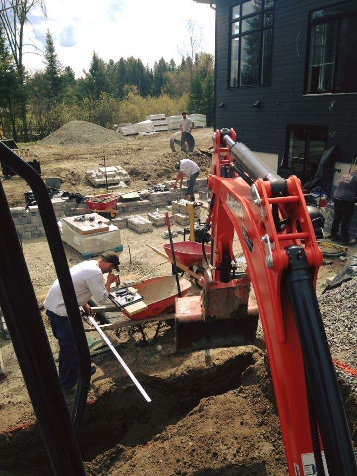 A large red excavator is being used to dig a hole in the ground