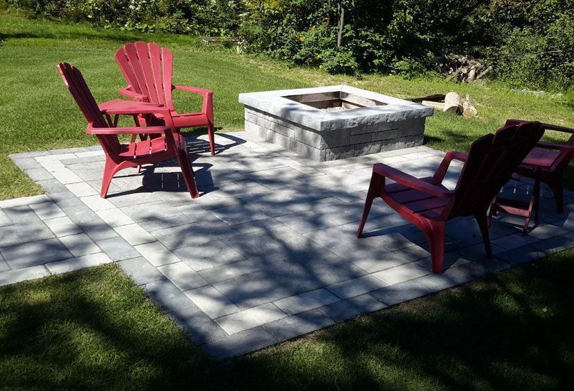 Un foyer au milieu d'un patio avec des chaises rouges.