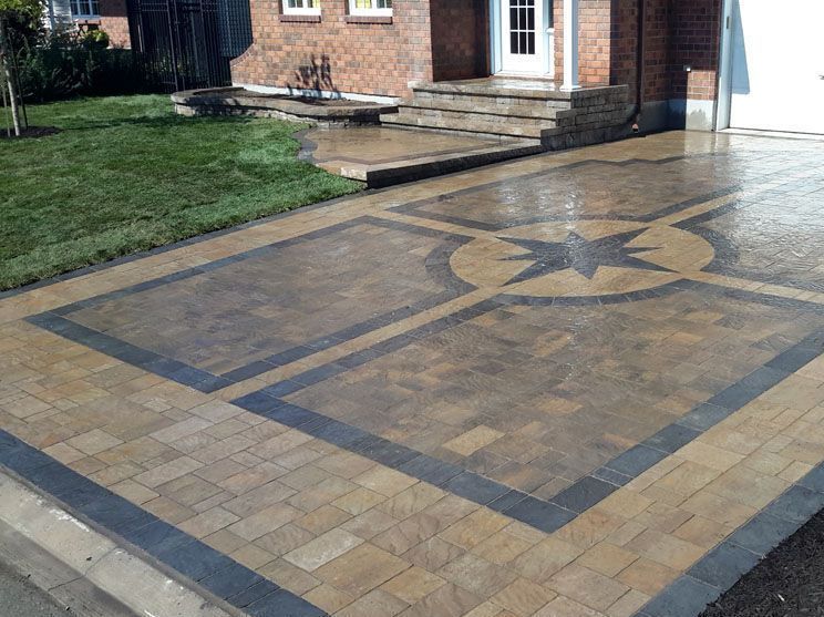 A brick driveway with a star design in the middle is in front of a brick house.