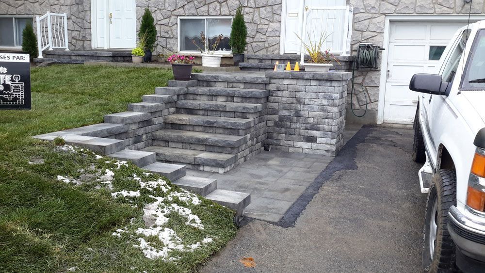 Un camion blanc est garé devant une maison en pierre.