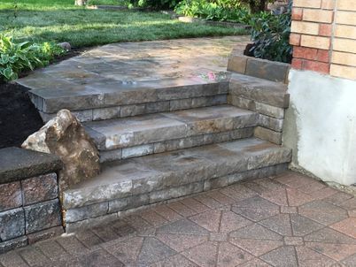 A set of stone steps leading up to a brick walkway.