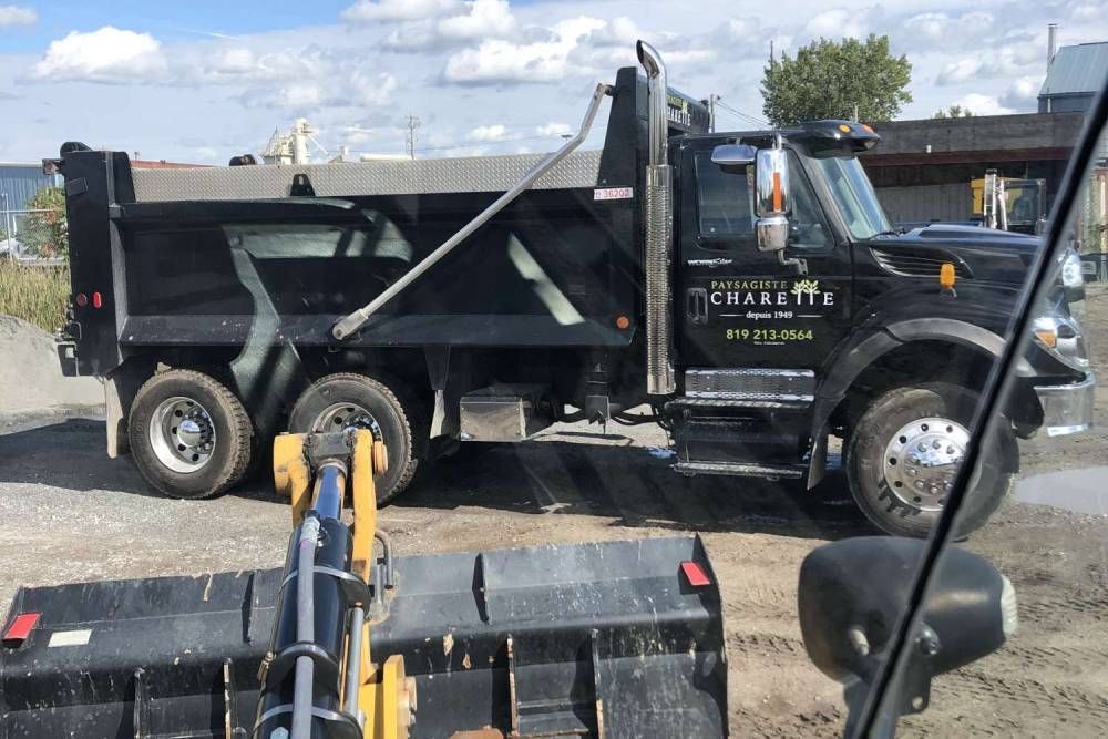 A dump truck is parked in a dirt lot next to a bulldozer.