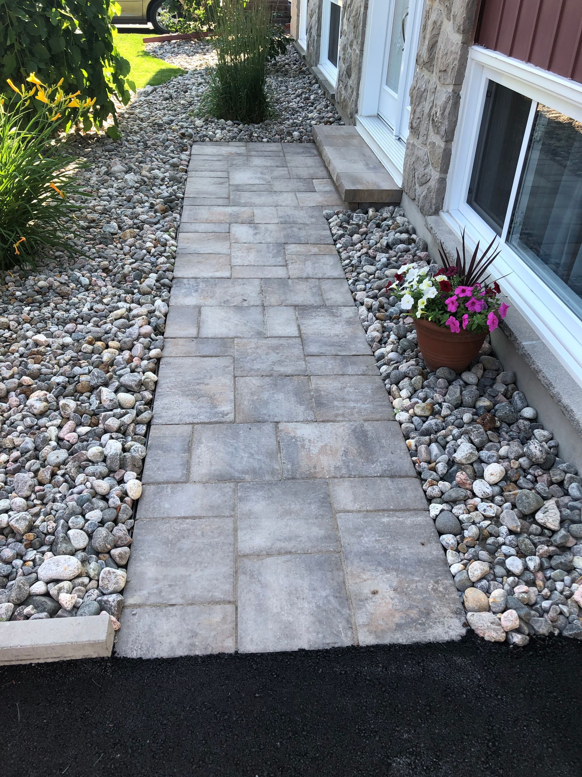 A stone walkway with a pot of flowers on the side