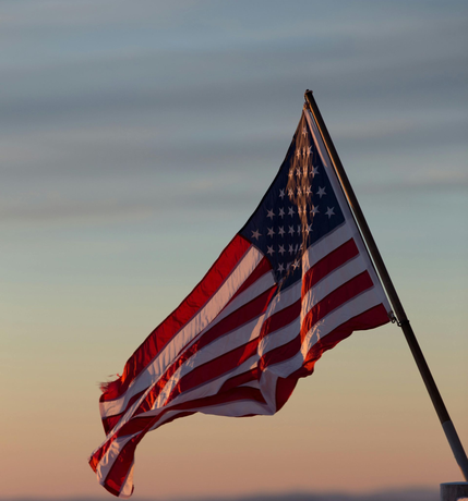 American flag waving against a dawn sky.