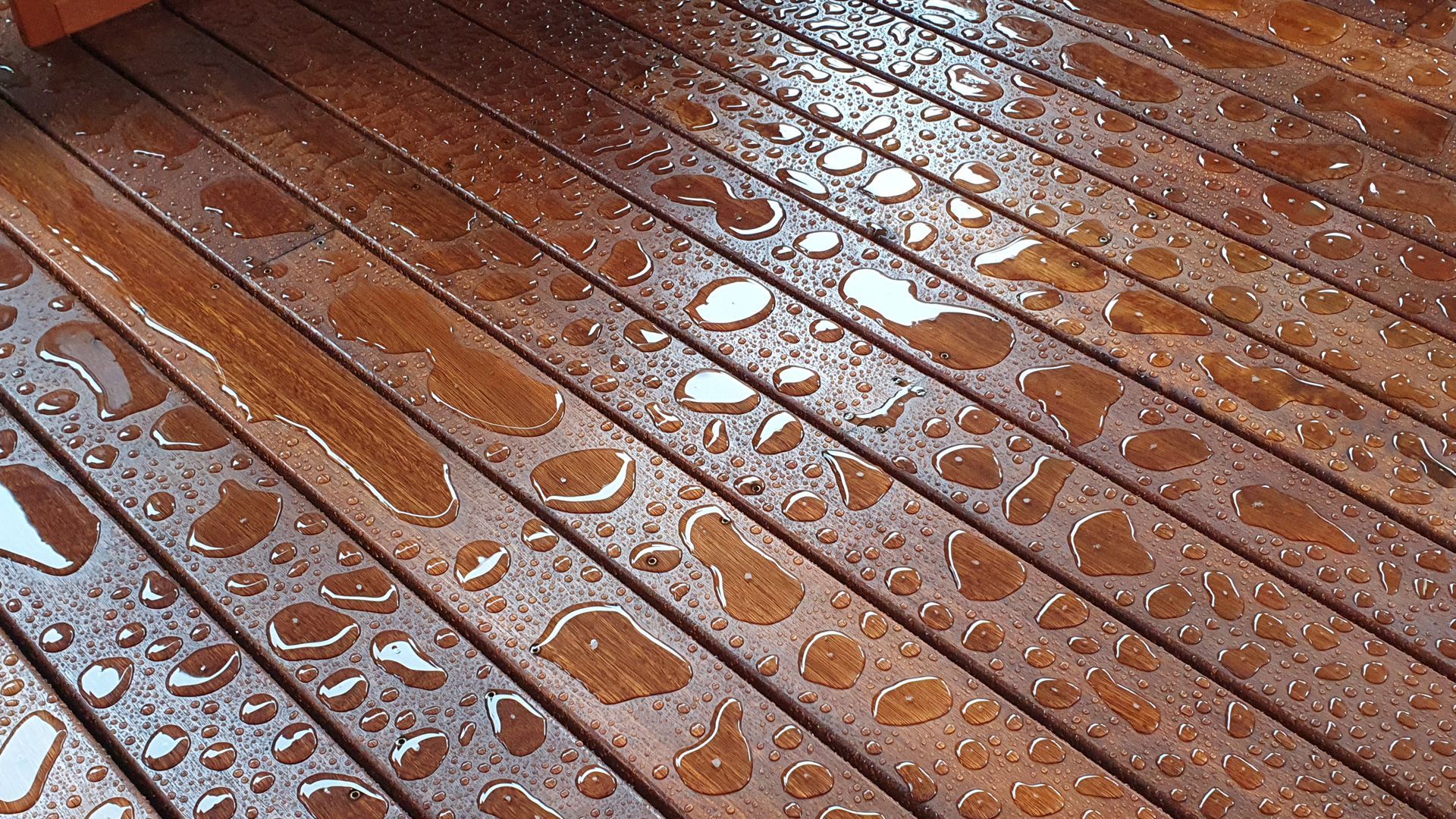 A close up of a wooden deck with water drops on it.