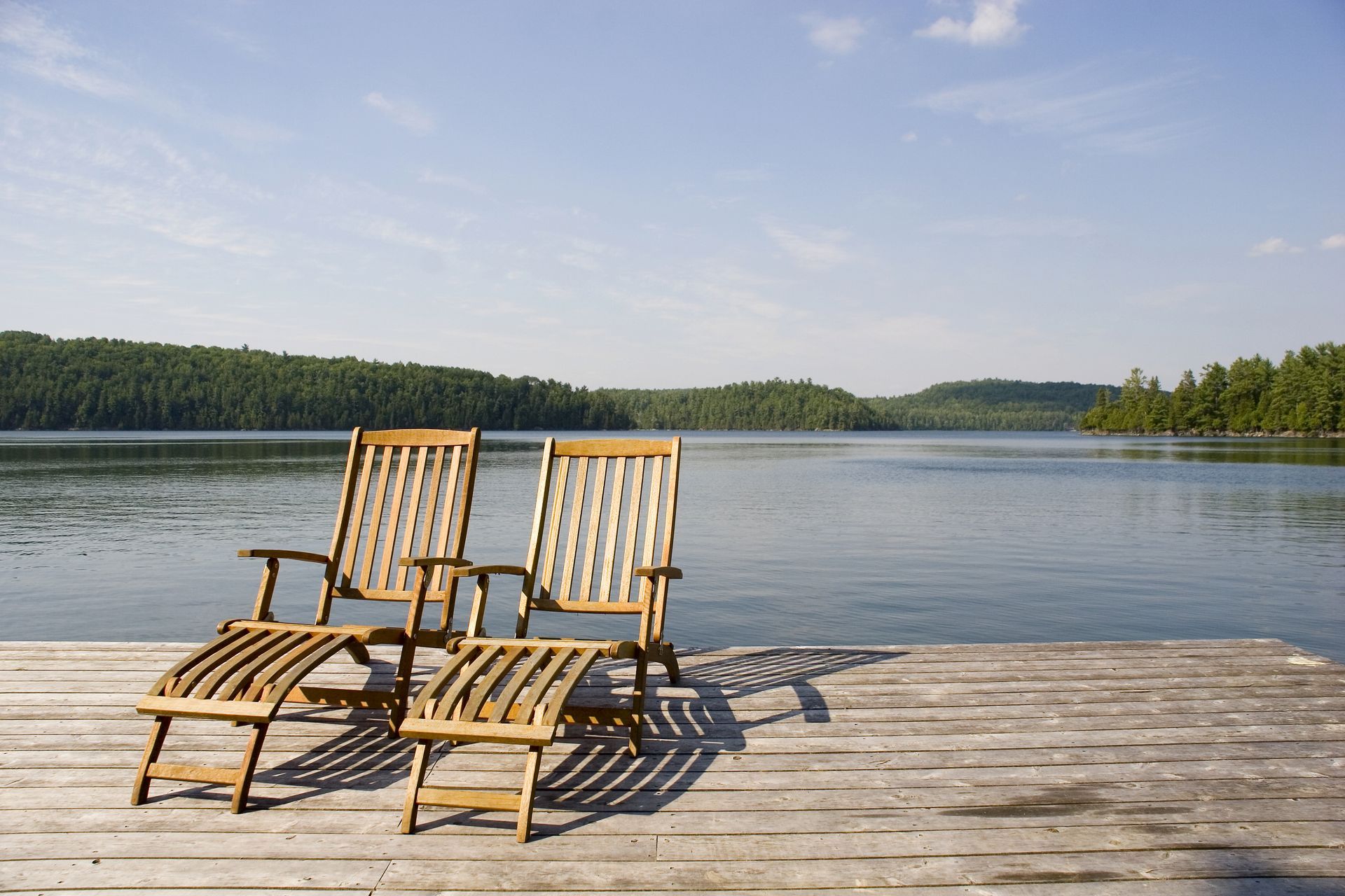 Two chairs on a dock overlooking a lake