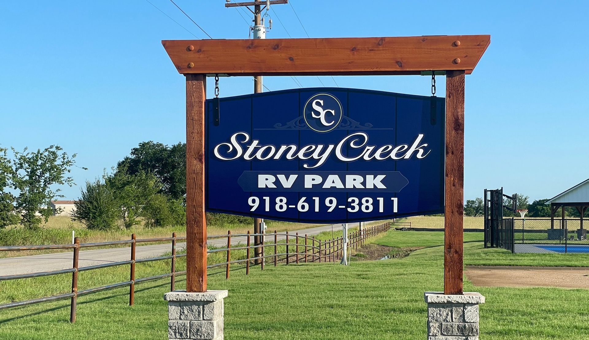 A stoney creek rv park sign is hanging from a wooden post