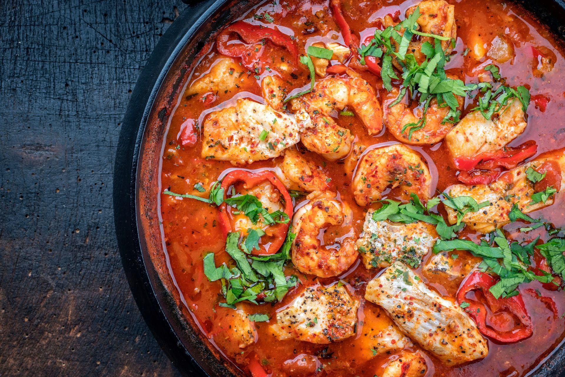 A close up of a bowl of stew with shrimp and chicken.
