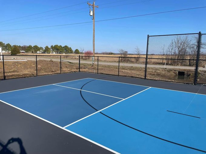 A blue basketball court with a fence around it