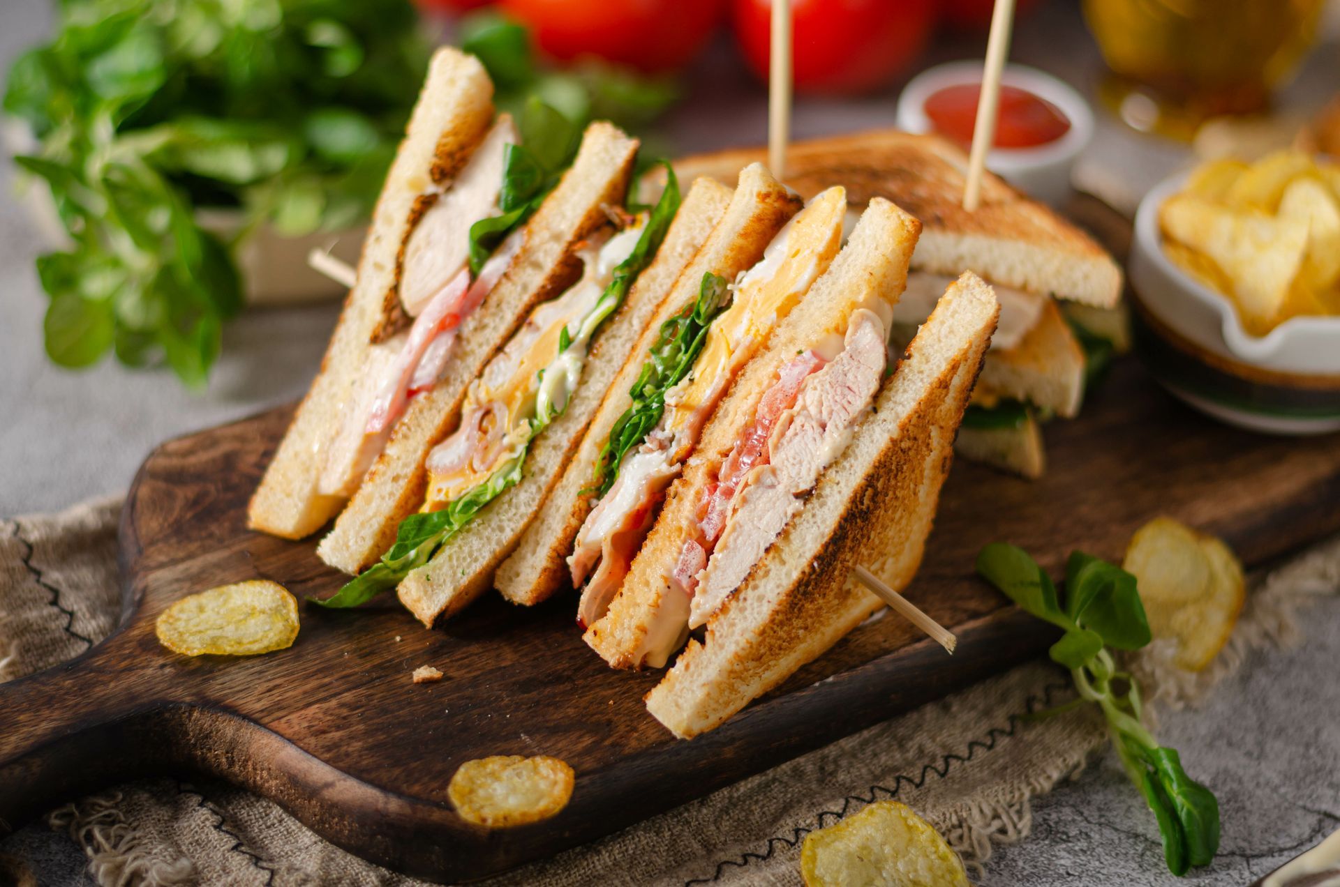 A club sandwich is sitting on top of a wooden cutting board.