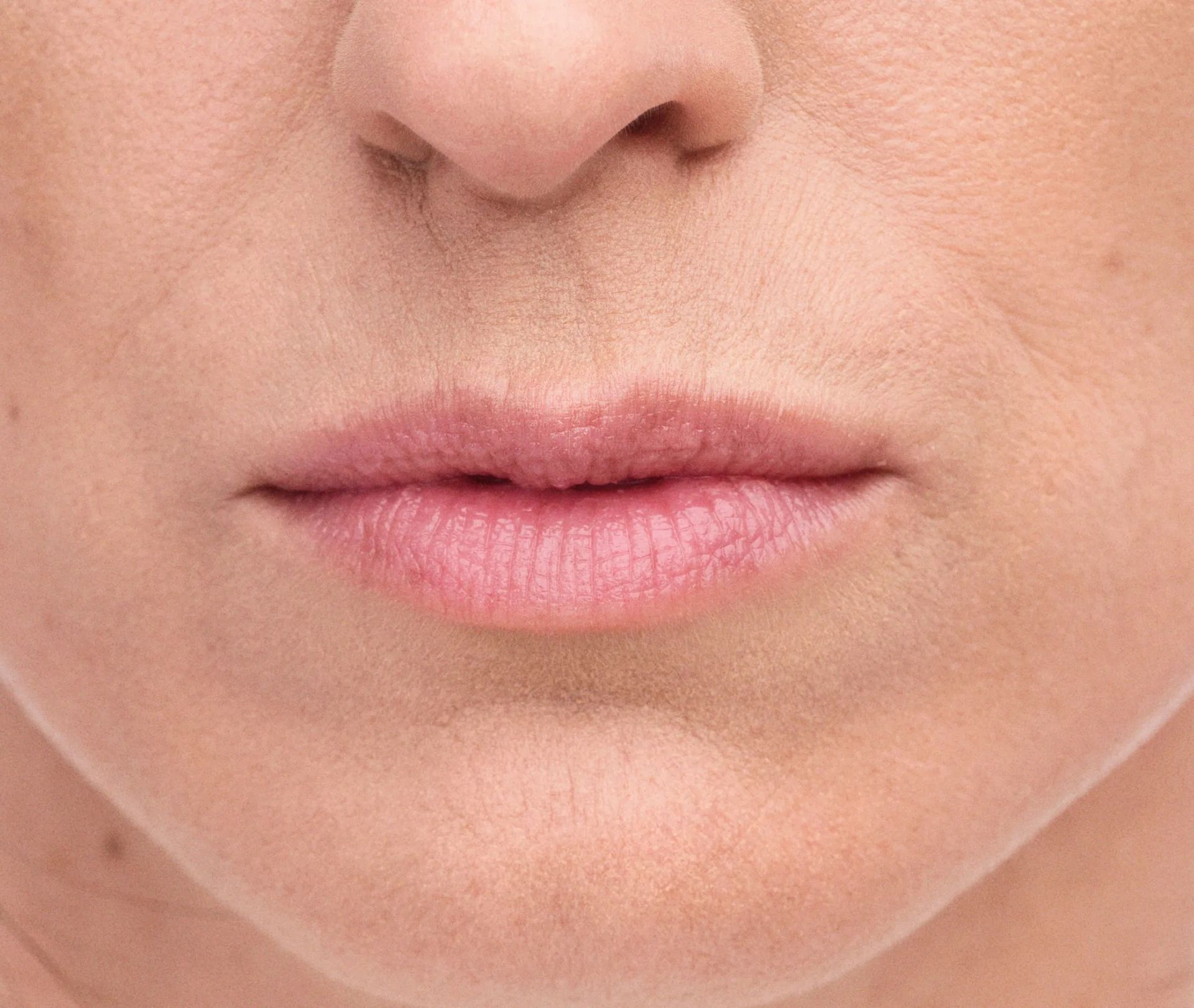 Close-up of a person's lips and nose. Pink lips, fair skin, some wrinkles.