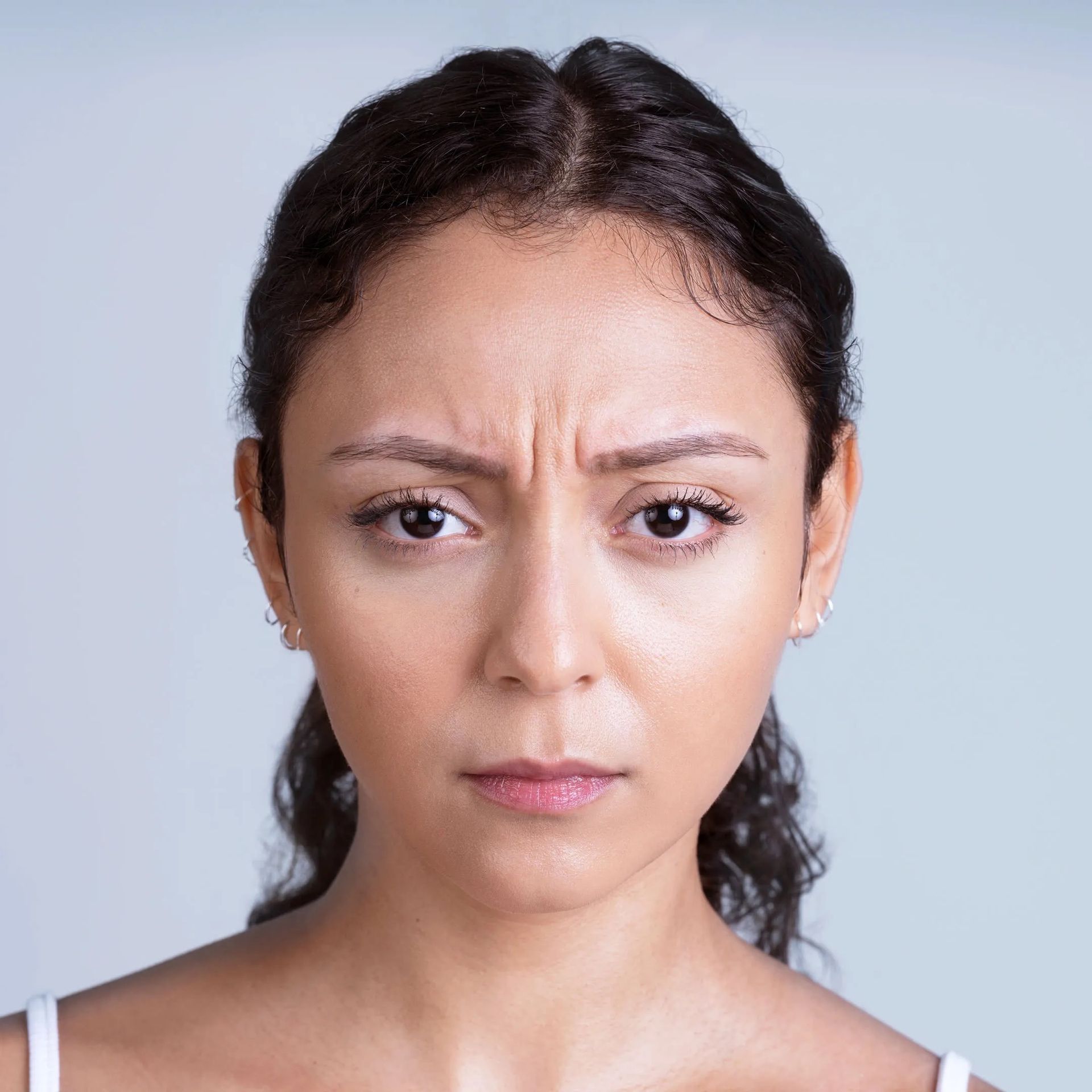 Woman with furrowed brow, looking directly at the viewer with a stern expression.