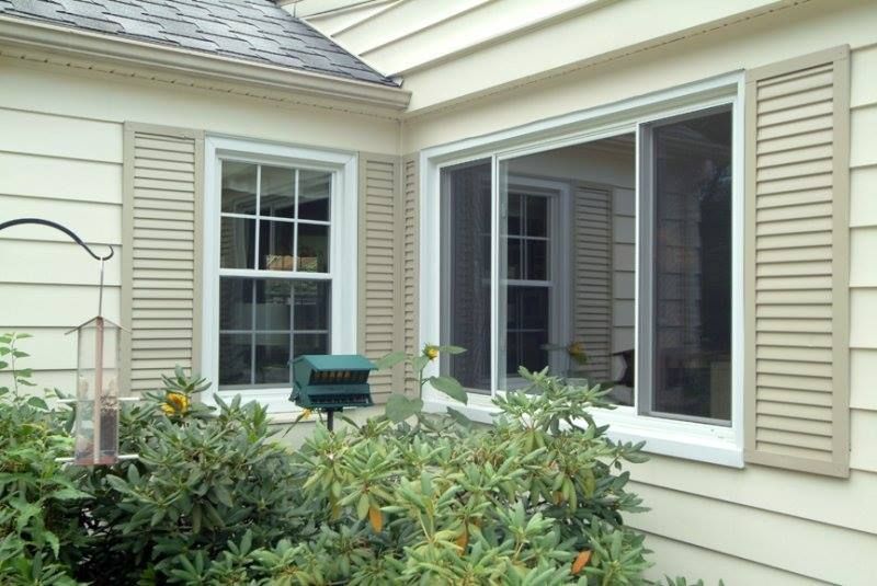 There are two windows on the side of a house.