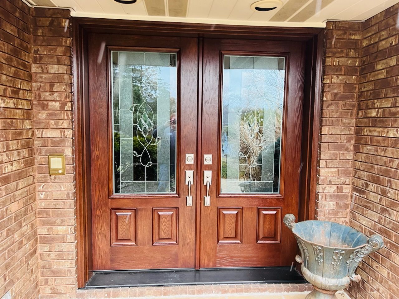 A brick building with a wooden door and a vase in front of it.