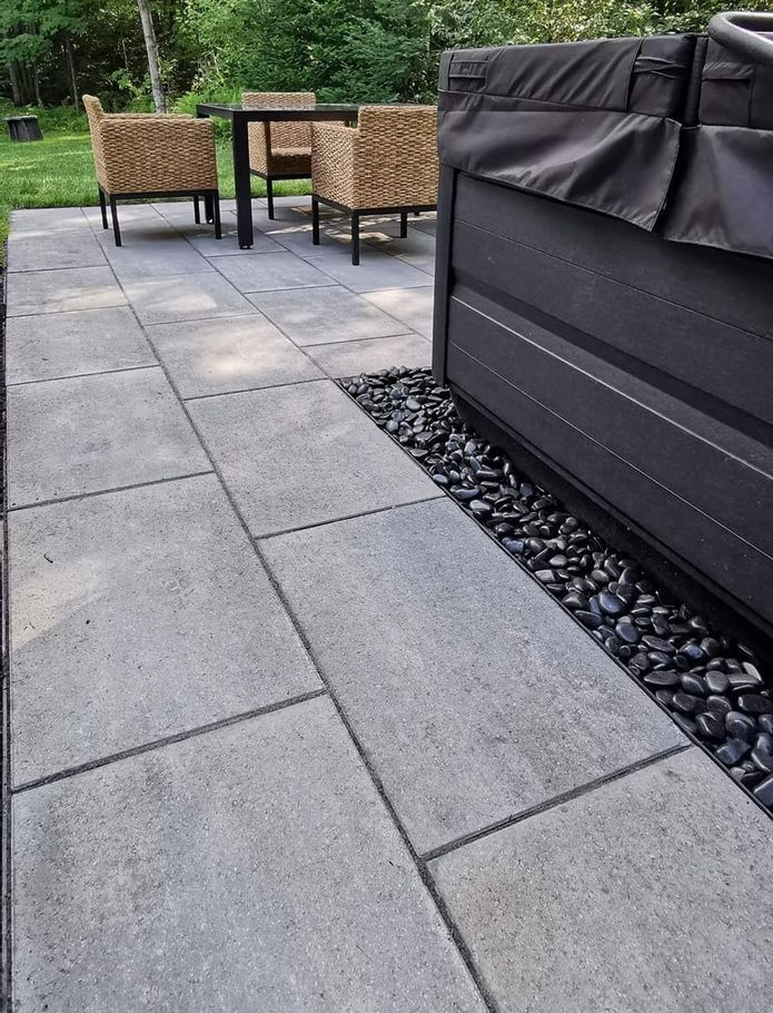 Un patio avec une table et des chaises à côté d'un bain à remous.