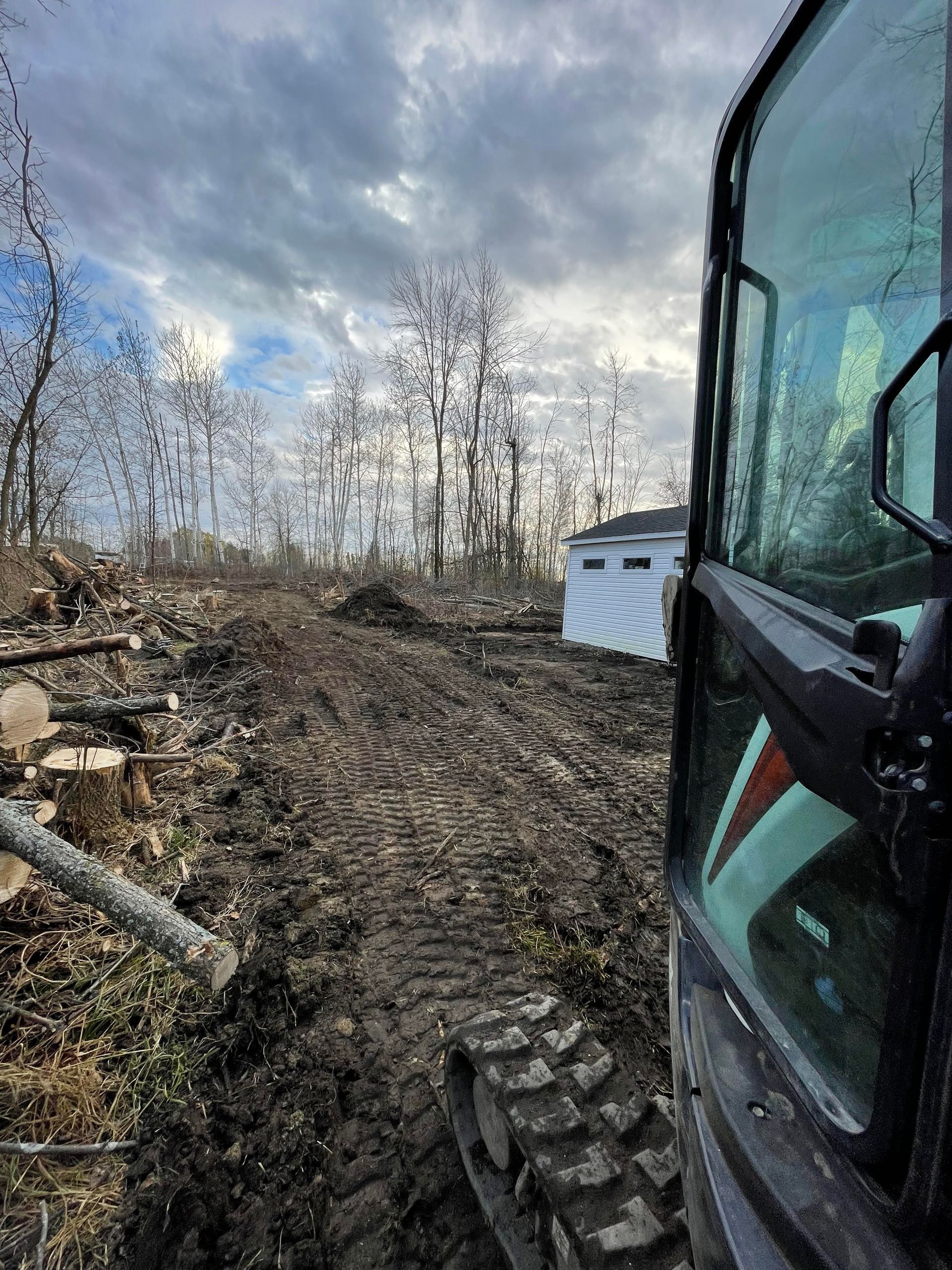 Un bulldozer roule sur un chemin de terre dans les bois.