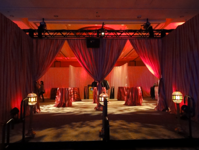 a room with red curtains above tables and lanterns