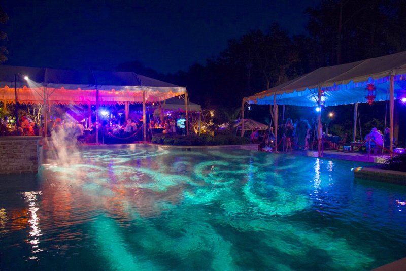 a large swimming pool is lit up at night with colorful designs