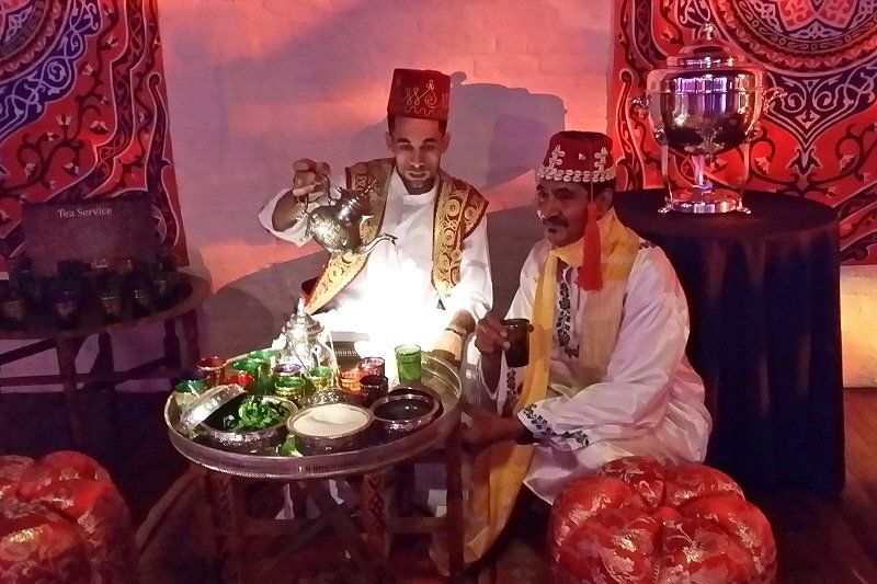 Interactive entertainment image showing Moroccan mint tea serving station with servers