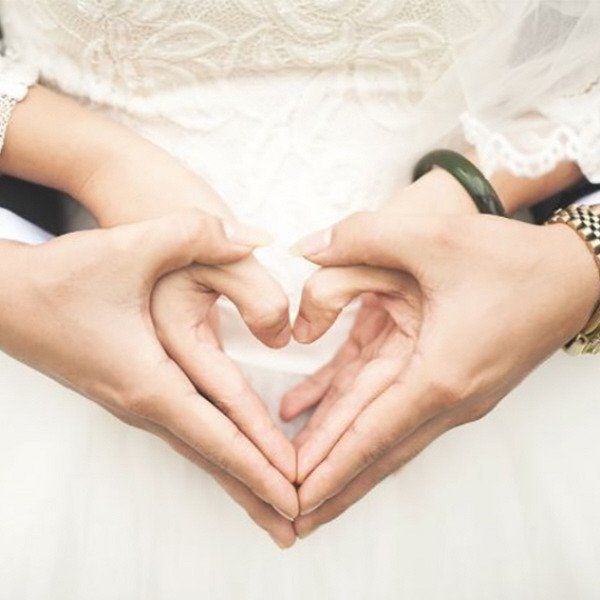 bride and groom with hands linked in heart shape