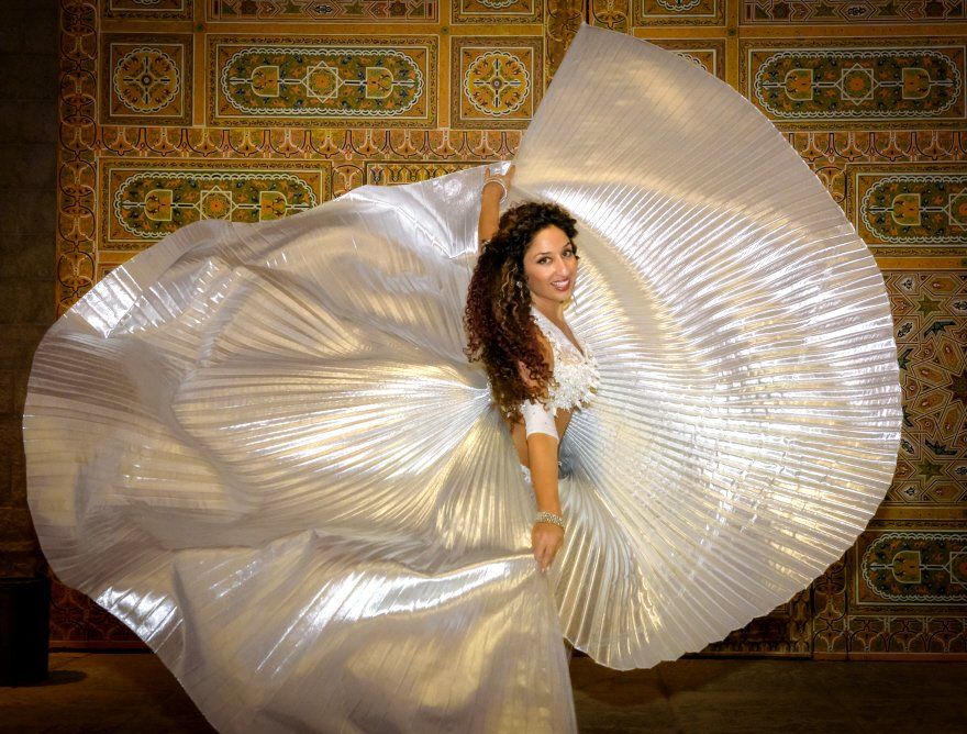a woman in an arabian style white dress dancing