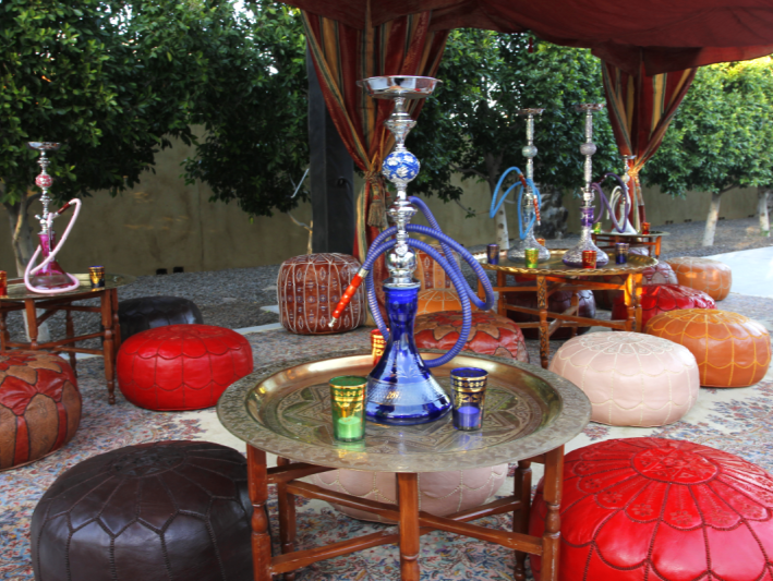 a table with hookahs and ottomans under a canopy