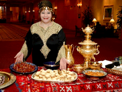 a woman is standing in front of a decorative table full of food.