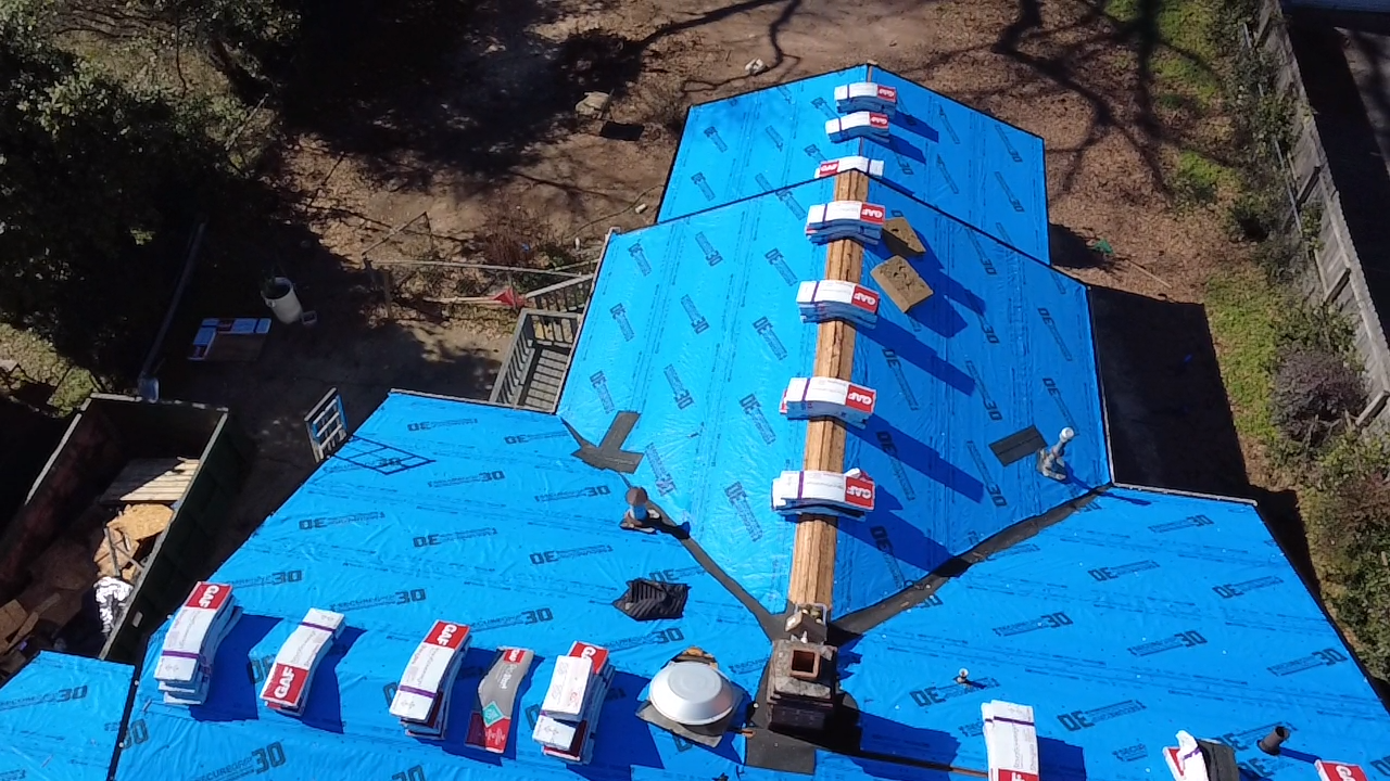 A white house with a wooden roof is being remodeled.