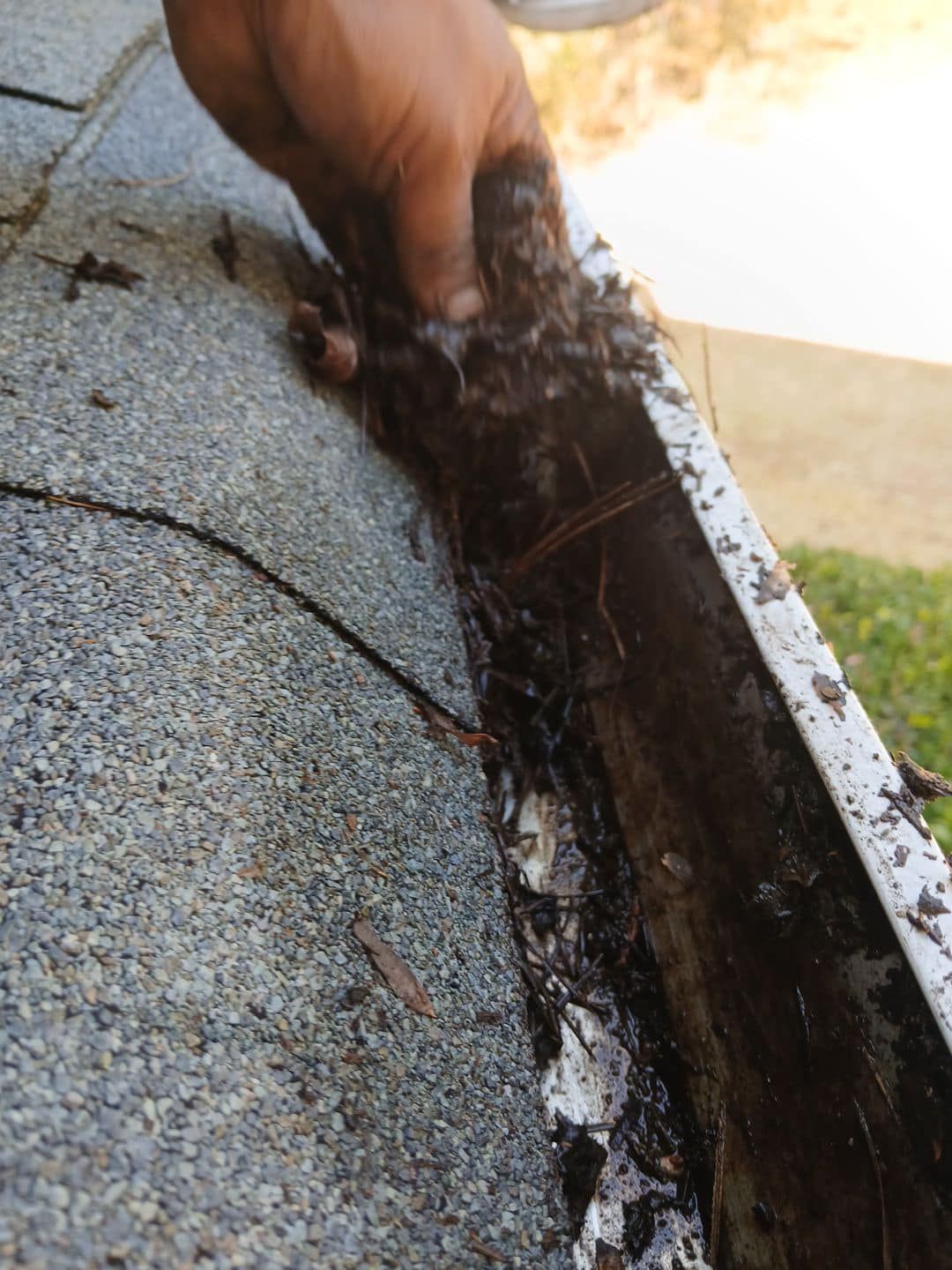 A person is cleaning a gutter on a roof.