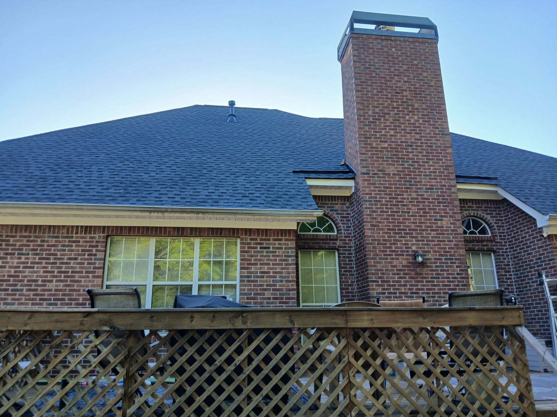 A brick house with a wooden deck and a chimney on the roof.