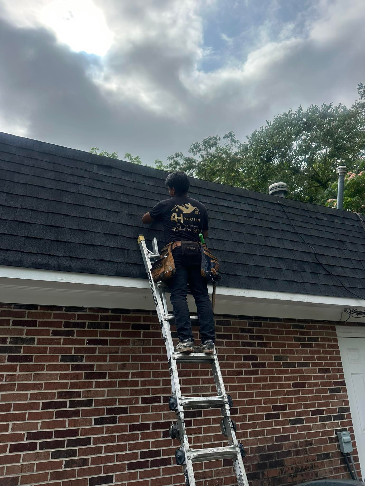 A man is standing on a ladder on top of a roof.