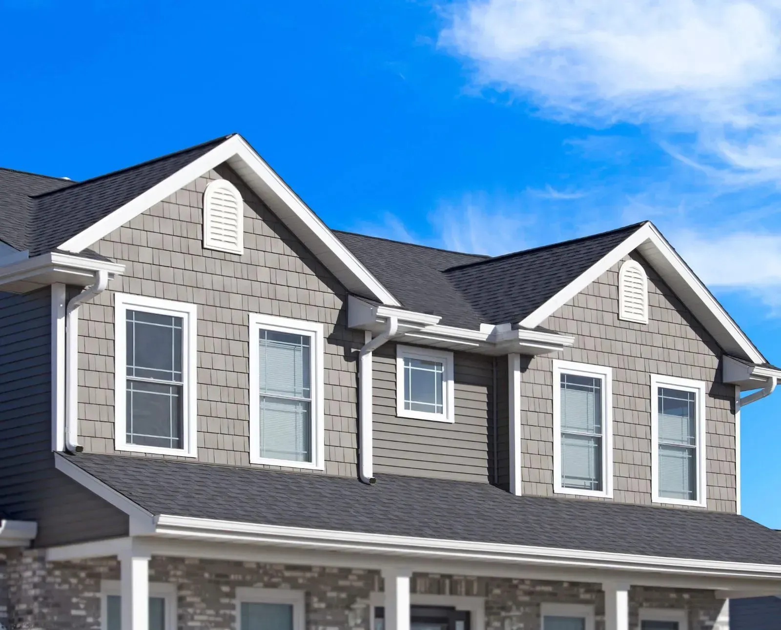 A gray house with a black roof and white trim
