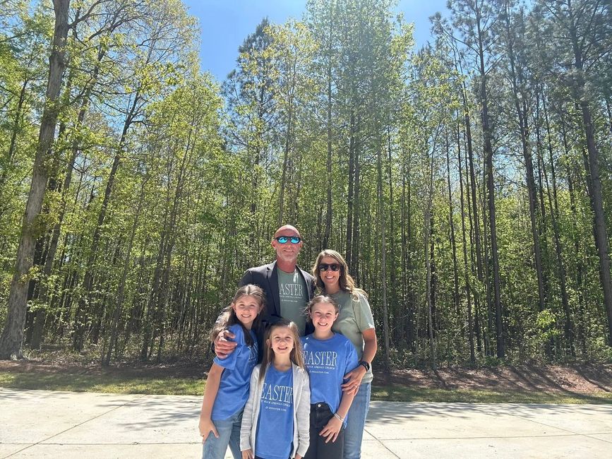 A family is posing for a picture in front of a forest.