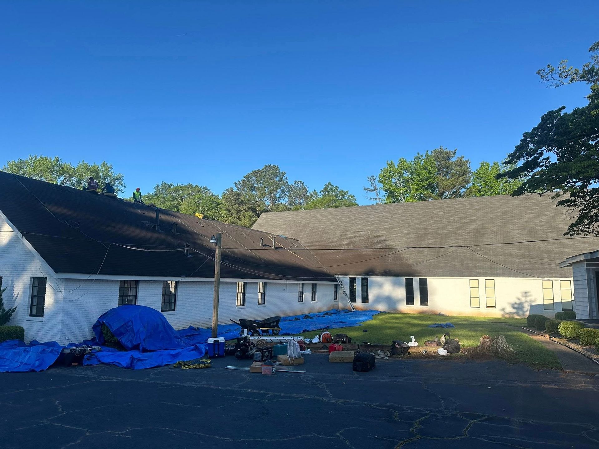 A large white house with a black roof is being remodeled.