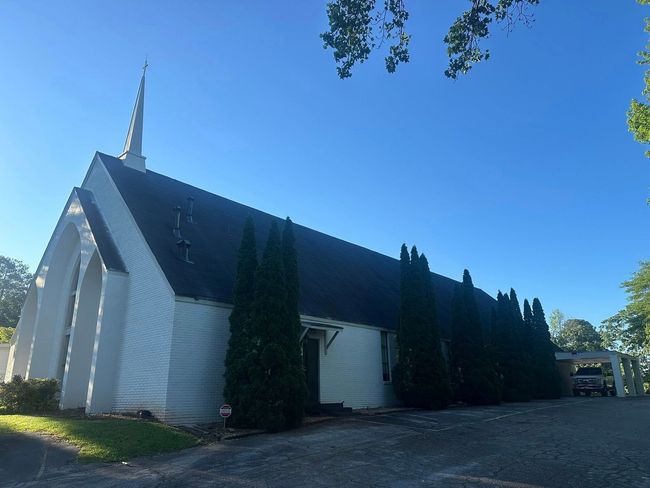 A white church with a black roof and a steeple