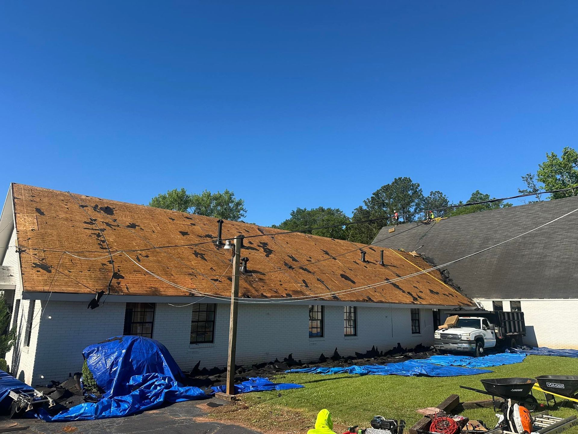 A white house with a brown roof is being remodeled.
