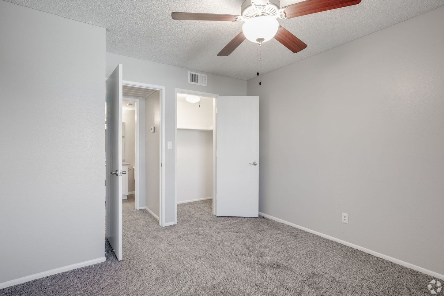 Bedroom with gray carpet, light gray walls, white doors, and a ceiling fan.