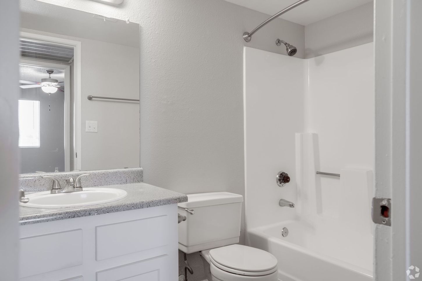 Bathroom with white vanity, toilet, and bathtub. Gray walls and granite countertop.