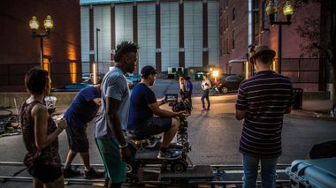 A group of people are standing around a camera on a cart.
