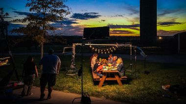 A group of people are sitting around a picnic table at night.